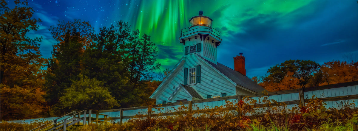 Mission Point Lighthouse  stands in a grassy field at night under a vivid green aurora borealis sky, with trees and a fence in the foreground.